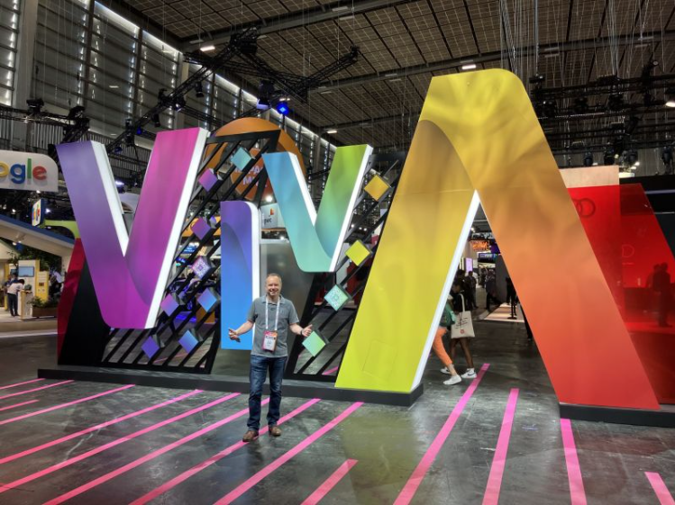 A man celebrating at #VivaTechnology in front of a colorful sign.